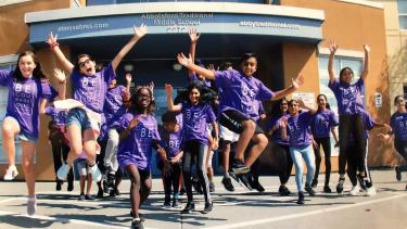 Students jumping with excitement in front of school